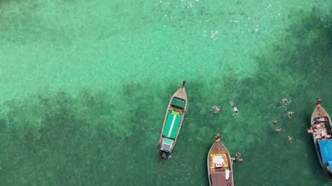 Top down aerial of longtail boat and swimmers in turquoise water Vídeos de archivo 333864873