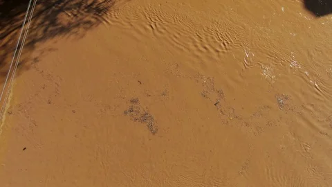 Top down aerial of muddy water, debris floating downriver into scary Stock Footage