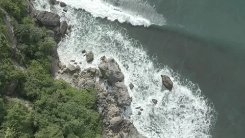 Top-Down Aerial of Ocean Waves Crashing Against Rocky Jungle Coastline Stock Footage 314368506