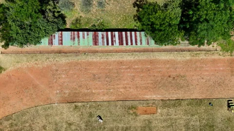 Top down aerial over rural dry soil athletics track in African village 動画素材 332893574