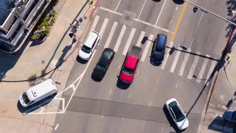 Top down aerial over sunny city intersection with cars crossing empty crosswalk. Stock Footage 346414473