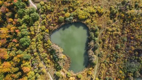 Top down aerial overview of a small mountain lake in an autumn fall forest. Stock Photos