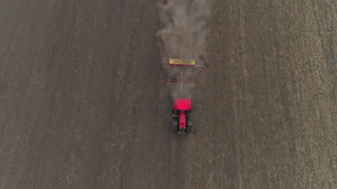 Top down aerial of red tractor cultivating or aerating or seeding in field Stock Footage 167551615