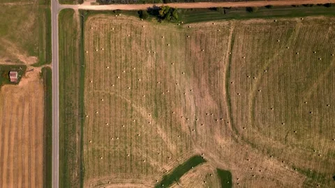 Top-down aerial of a road beside a harvested field with hay bales Video stock 345531194