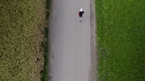 Top down aerial - A runner is training on a narrow asphalt road. Stock Footage 247231366