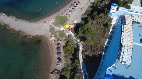 Top down aerial shot of a narrow beach with umbrellas and rocks. Stock Footage 343939627