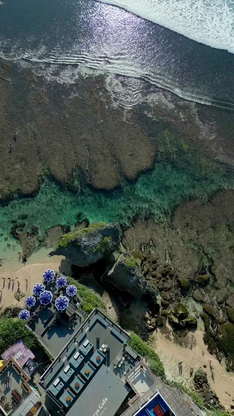 Top down aerial shot over Uluwatu's dramatic rocky coastline revealing a hidden Stock Footage 340551280