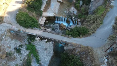 Top down aerial shot of a rustic dirt road bridge above a waterfall Stock Footage 343961629