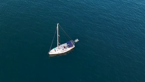 Top Down Aerial Shot of a White Sailboat Anchored in a Blue Sea Stock Footage 317090063