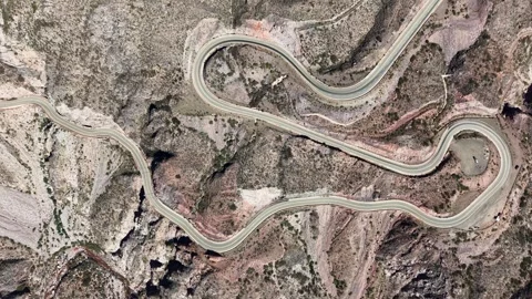 Top-down aerial shot of a winding mountain road forming a zigzag pattern. Stock Footage 335774083