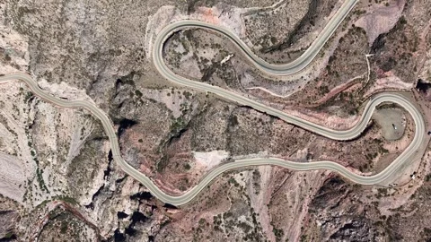 Top-down aerial shot of a winding mountain road forming a zigzag pattern. Stock Footage 336690541