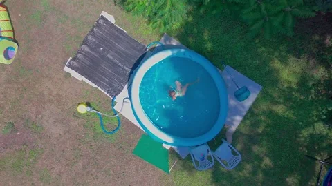 Top Down Aerial Spinning Shot of Child Twirling in Blue Inflatable Backyard Stock Footage 340542154