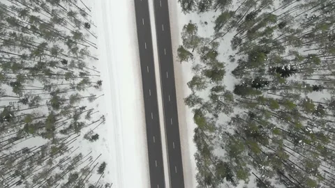 Top down aerial spinning view of snow covered forest with a two-lane road Stock Footage 148427736