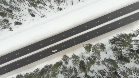 Top down aerial spinning view of snow covered forest with a two-lane road Vidéo 151037580