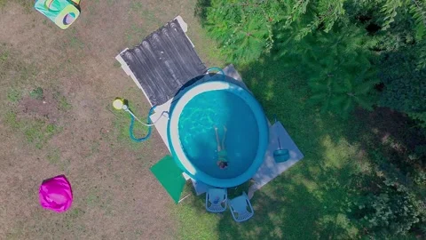 Top Down Aerial Static Shot of Child Swimming and Sitting in Blue Inflatable Stock Footage 340542103