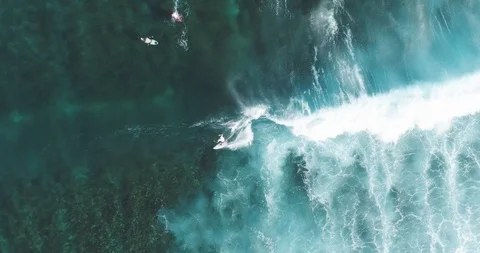 Top Down Aerial tracking shot on skilled male surfer riding a huge wave on a Stock Footage 125330997
