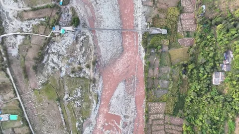 Top down aerial tracking shot of a narrow suspension footbridge spanning a .. Stock-Footage 348470224