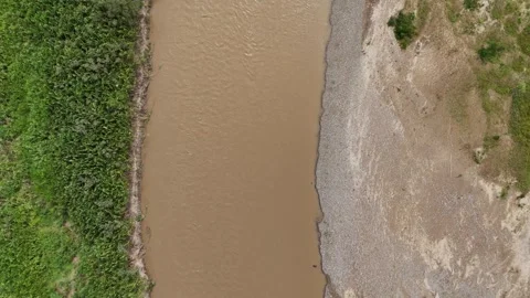 Top down aerial tracking of turbid river with green vegetation. Stock Footage 340515046