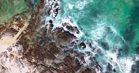 Top Down Aerial of Turquoise Ocean Waves and Rocky Coastal Shoreline Stock Footage 330718272