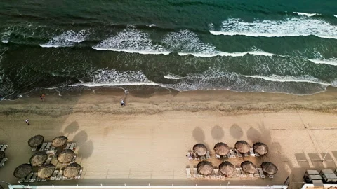 Top down aerial view of beach loungers and umbrellas by the shore Stock Footage 342090023