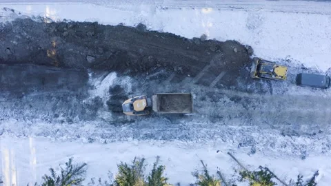 Top-down aerial view of the bulldozer pushing and leveling the soil in winter Stock Footage 148484314