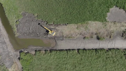 Top down aerial view of Camargue wetland with yellow excavator digging on dark 스톡 동영상 337977955