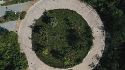 Top down aerial view to a car driving in roundabout. Automobile in greenery Stock Footage 233429626