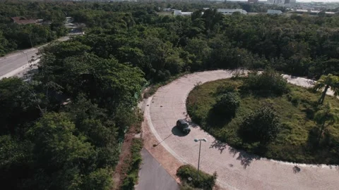 Top down aerial view to a car driving in roundabout. Automobile in greenery Video stock 233429689