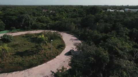 Top down aerial view to a car driving in roundabout. Automobile in greenery Stock Footage 233429886