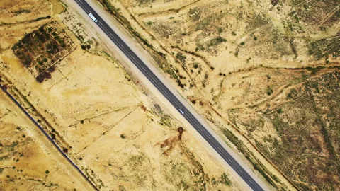 Top-down aerial view of a car on a desert road shot with rotating camera Video stock 304470335