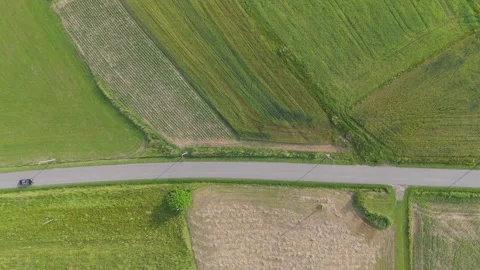 Top down aerial view of a car driving along a straight rural road cutting Stock-Footage 324520724
