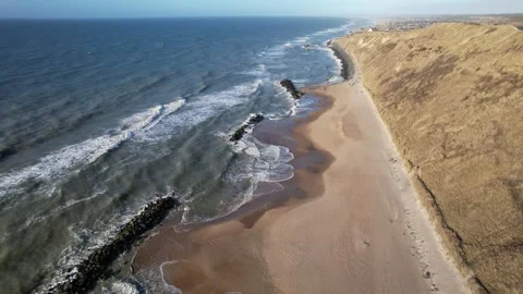 Top down aerial view of coastal village and sandy beach with breakwaters Stock Footage 343538996