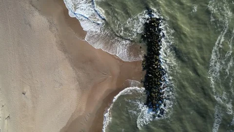 Top down aerial view of coastal village and sandy beach with breakwaters Stock Footage 343539035