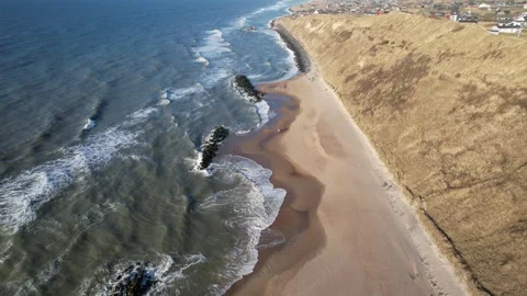 Top down aerial view of coastal village and sandy beach with breakwaters Stock Footage 343539042