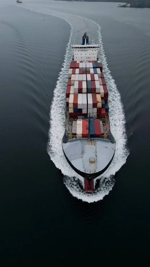 Top-down aerial view of container ship sailing through calm sea, creating Video stock 324855973