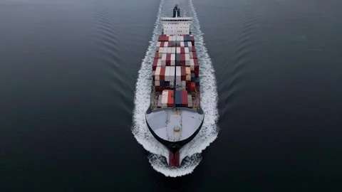 Top-down aerial view of container ship sailing through calm sea, creating symmet 库存影片 325740881