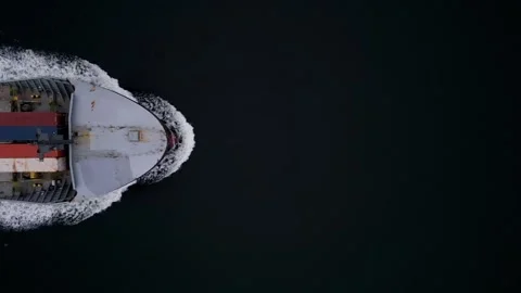 Top-down aerial view of container ship cutting through dark water, leaving white 库存影片 325741085