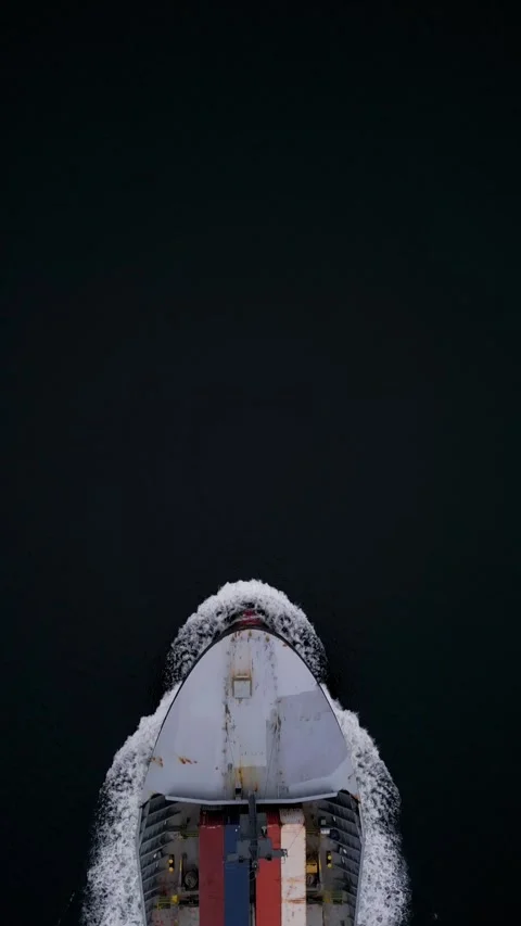 Top-down aerial view of container ship cutting through dark water, leaving white Stock-Footage 325741091