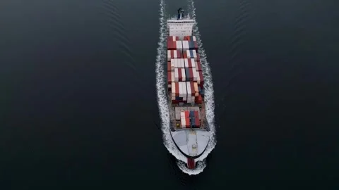 Top-down aerial view of container ship sailing through calm sea, creating symmet 库存影片 325741187