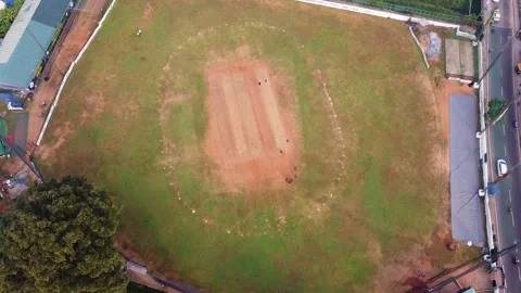 Top-down aerial view of a cricket match being played on a green field with a Stock Footage 324958937
