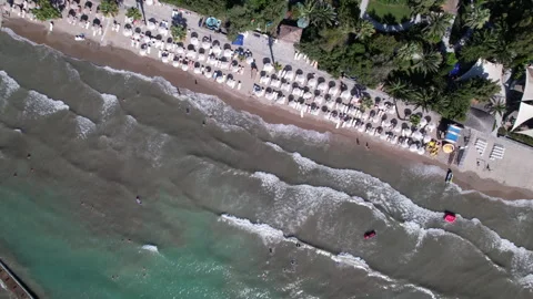 Top-down aerial view of a crowded sandy beach with waves 스톡 동영상 333459265