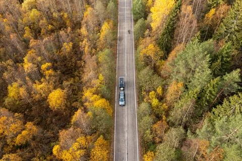 Top-down aerial view of a dark SUV towing a black camper trailer driving on a Stock Photos