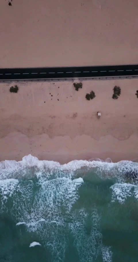Top-down aerial view of a deserted sandy beach with turquoise ocean waves Stock Footage 344815953