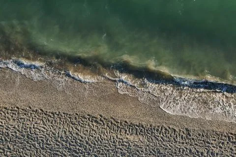 Top down aerial view of emerald sea waves crashing on sandy coast. Фото