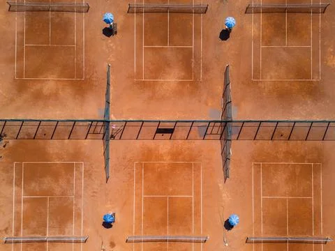 Top-down aerial view of empty clay tennis courts with nets and umbrellas. Geo Stock Photos