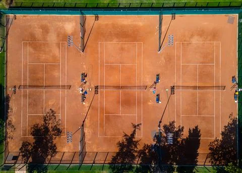 Top-down aerial view of empty clay tennis courts with nets and umbrellas. Geo Stock Photos