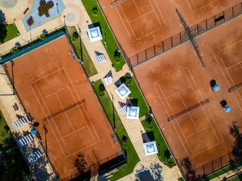 Top-down aerial view of empty clay tennis courts with nets and umbrellas. Geo Stock Photos