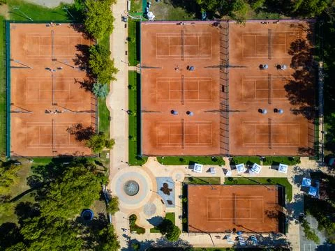 Top-down aerial view of empty clay tennis courts with nets and umbrellas. Geo Stock Photos