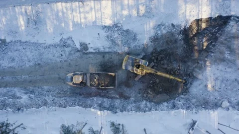 Top-down aerial view of the excavator loading soil on a dump truck in winter Stock Footage 148483942
