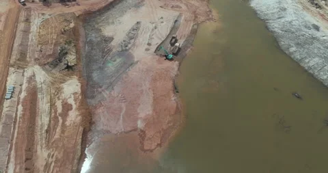 Top-down aerial view of excavator loading dump truck near muddy river.  Stock Footage 343283655
